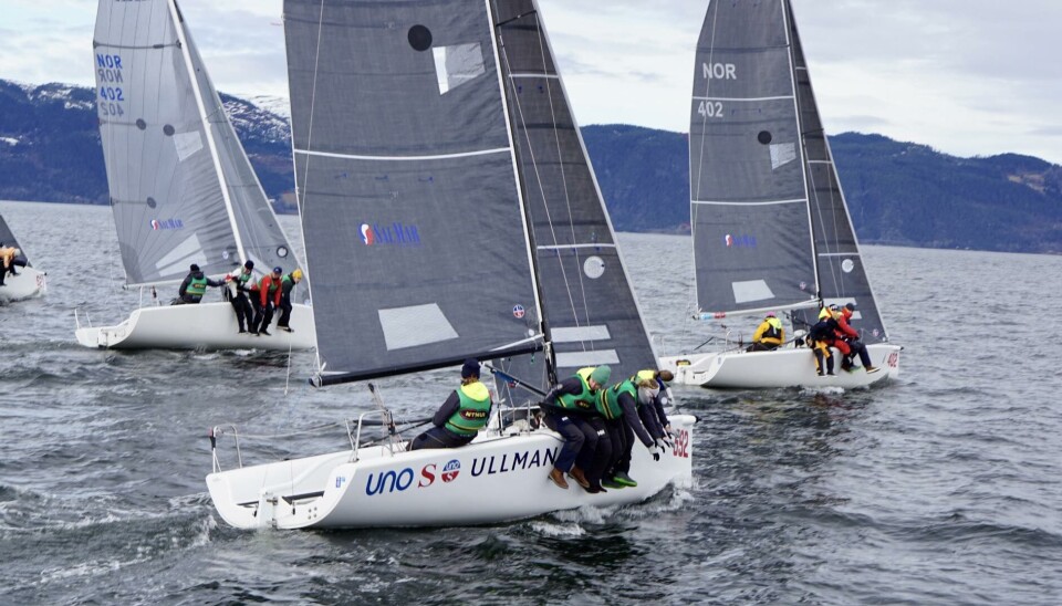 Starten har gått, og båtene er i full fart. Med vinden som fyller seilene, justerer mannskapene posisjonen for å sikre seg en god plassering